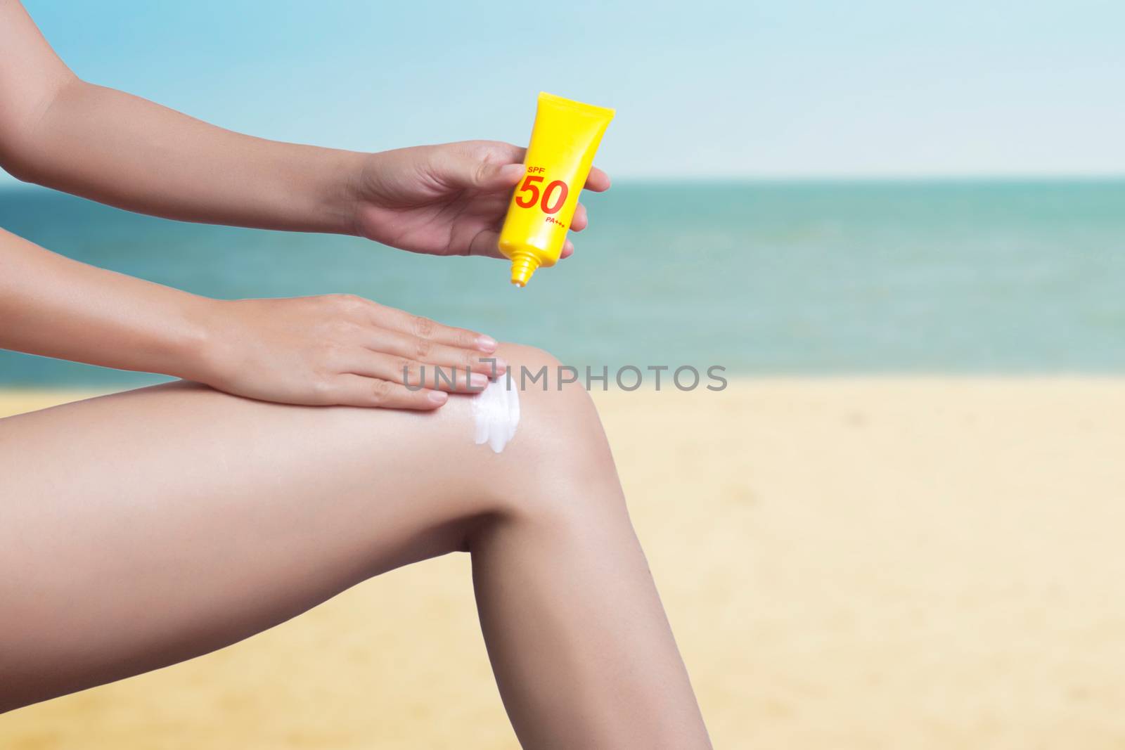 woman applying sunscreen on her leg with sea background. SPF sunblock protection concept. Travel vacation , clipping path include by asiandelight