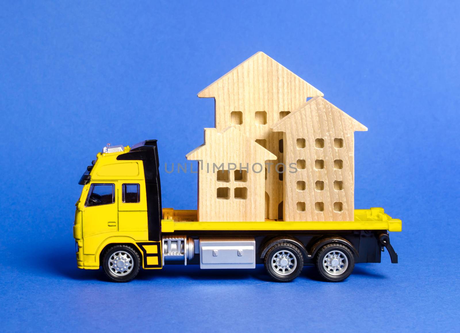 A cargo truck transports houses. Concept of transportation and cargo shipping, moving company. Construction of new houses and objects. Logistics and supply. Move entire buildings