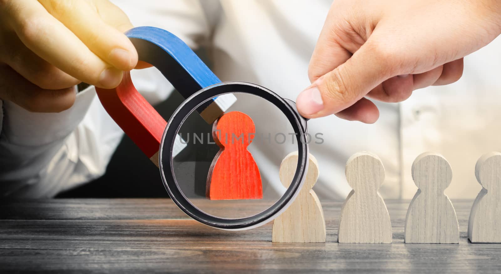 A magnifying glass looks at a businessmans hand draws a red figure from the team with a magnet. The concept of toxic and non-competent worker. Increase team efficiency. leader forms a team. by iLixe48