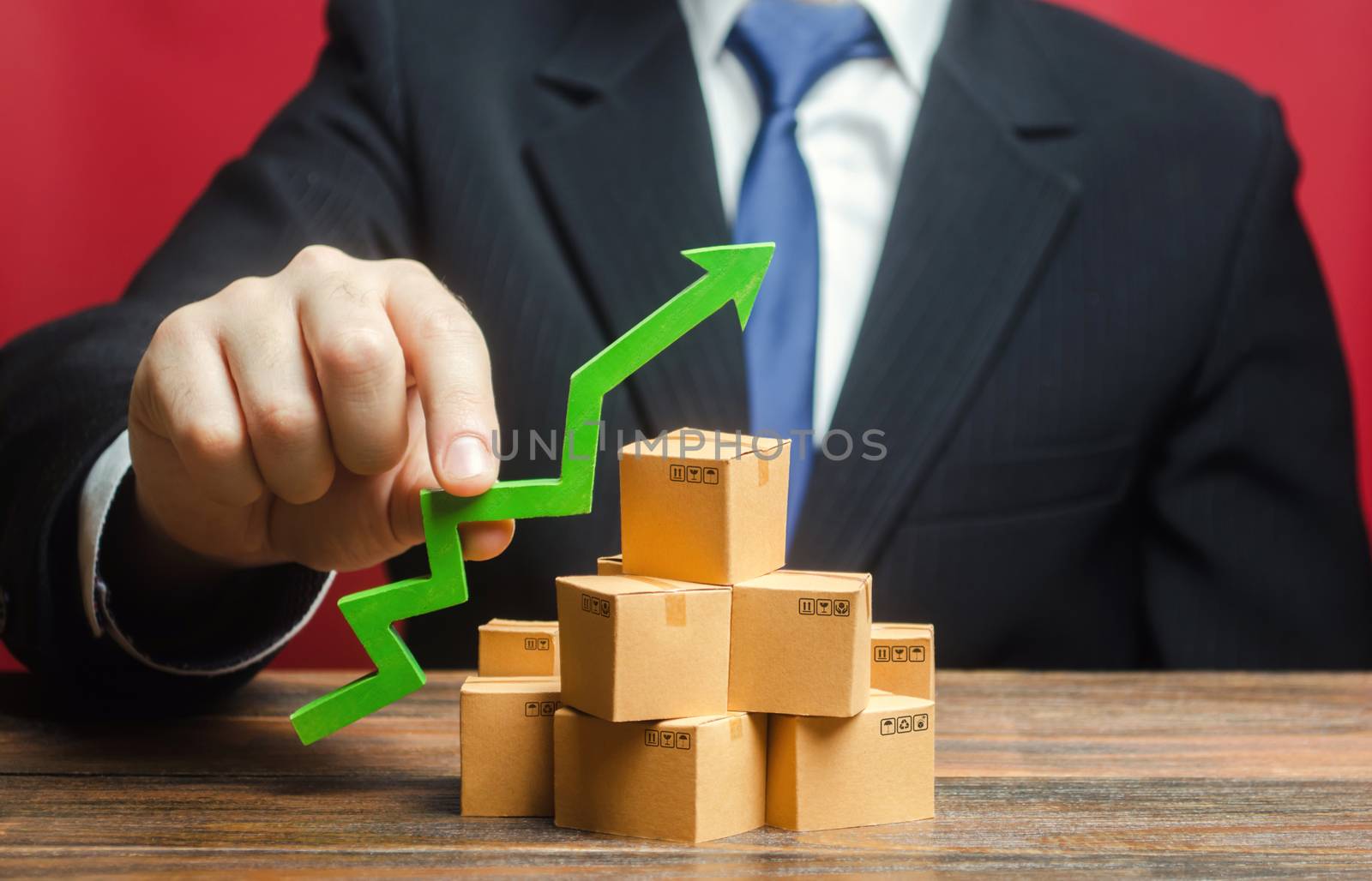 Businessman holding a green arrow up over boxes. Boost sales rate. Increasing production of goods, expanding export opportunities, finding markets. Tactics and strategy, marketing. Value added goods by iLixe48