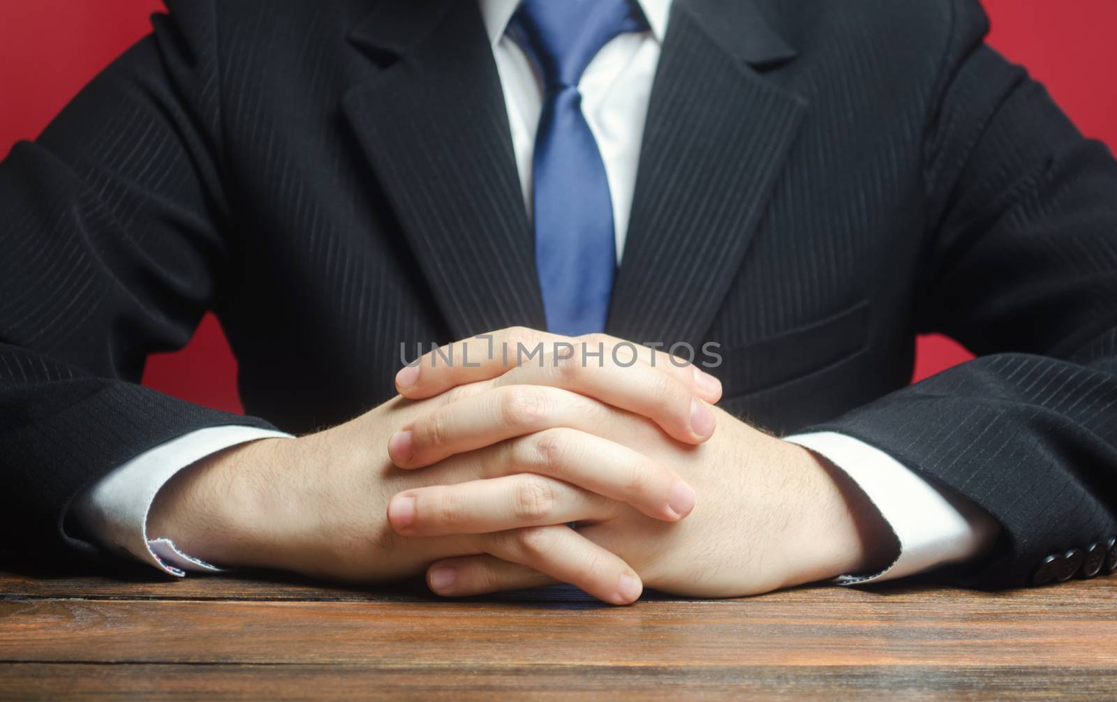 A man sits at the table with folded arms. Ready to listen to news and criticism. Serious talk. Calmly. Communication and body expressions. Job interview. Make an informed decision. Humility.