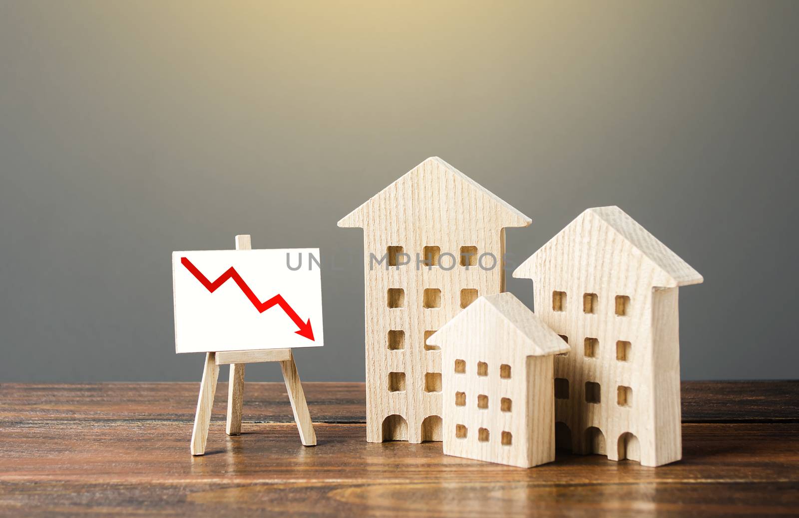 Wooden houses residential buildings and an easel with a red down arrow. Fall of real estate market. Value cost decrease. Bad liquidity attractiveness. Cheap rent. Reduced demand, recession. Low sales by iLixe48