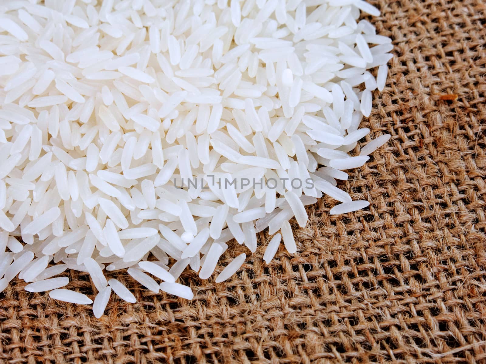 Thai jasmine rice in sack, white rice on burlap sack background with rice grain close up by asiandelight