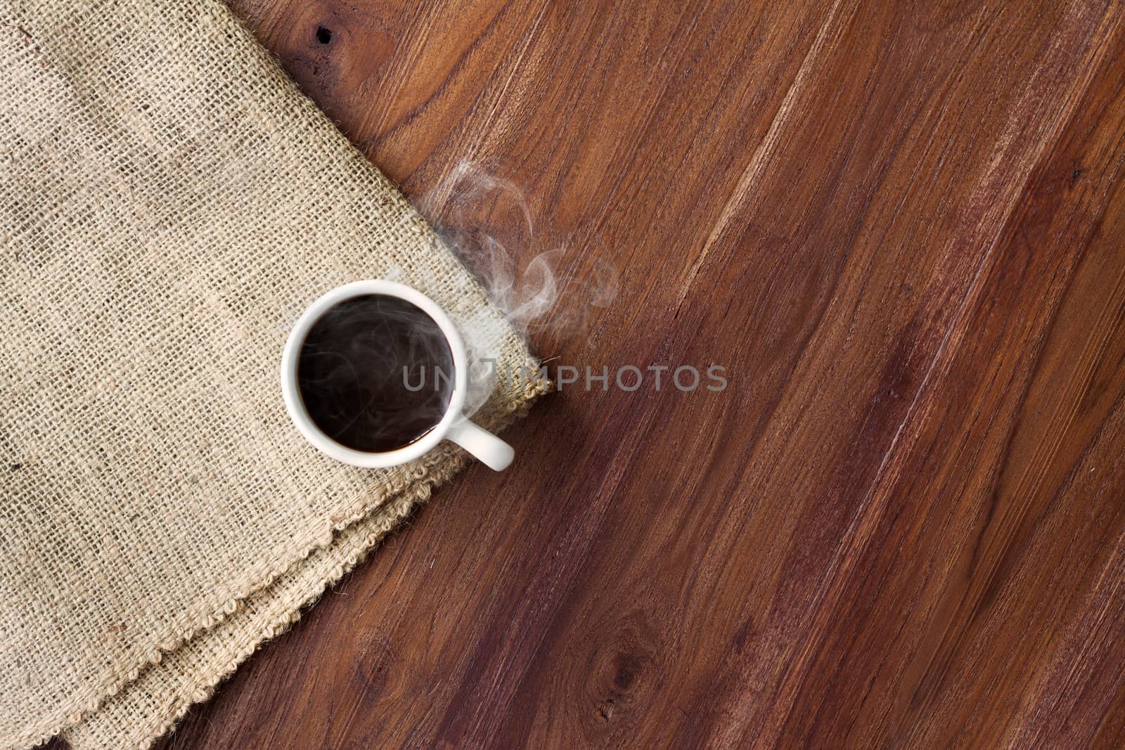 hot coffee with smoke on sack background over wooden table by asiandelight