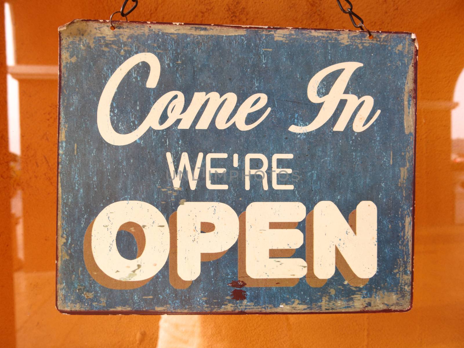 Vintage open sign board word 'Come in We're Open' through the glass of window on Cafe at restaurant open door by asiandelight