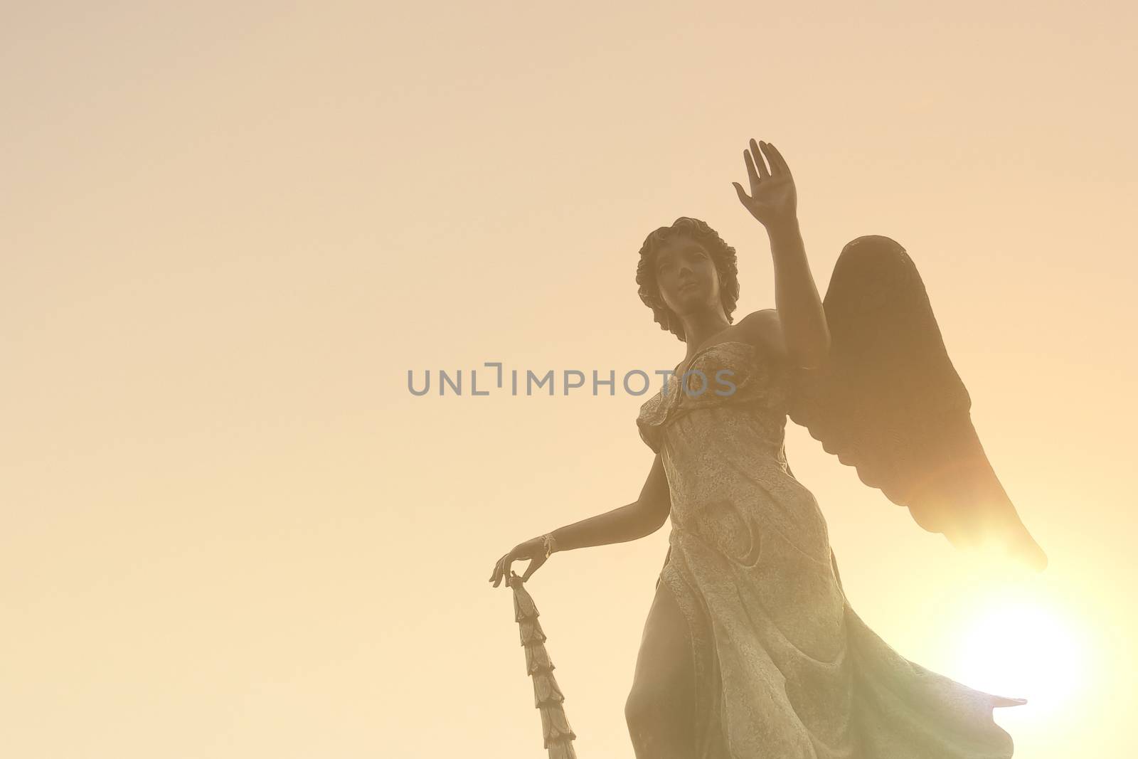 Beautiful angel statue in sunlight before sunset, faith and religion concept