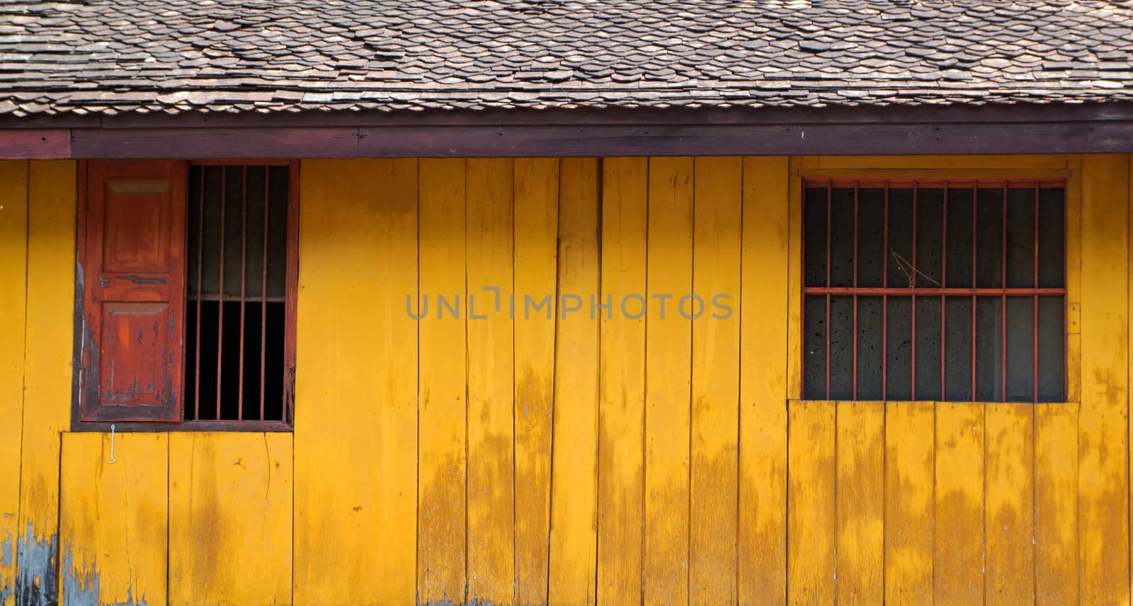 Vintage simple wood house with yellow wooden wall and rustic exterior window shutters at countryside in Asia by asiandelight