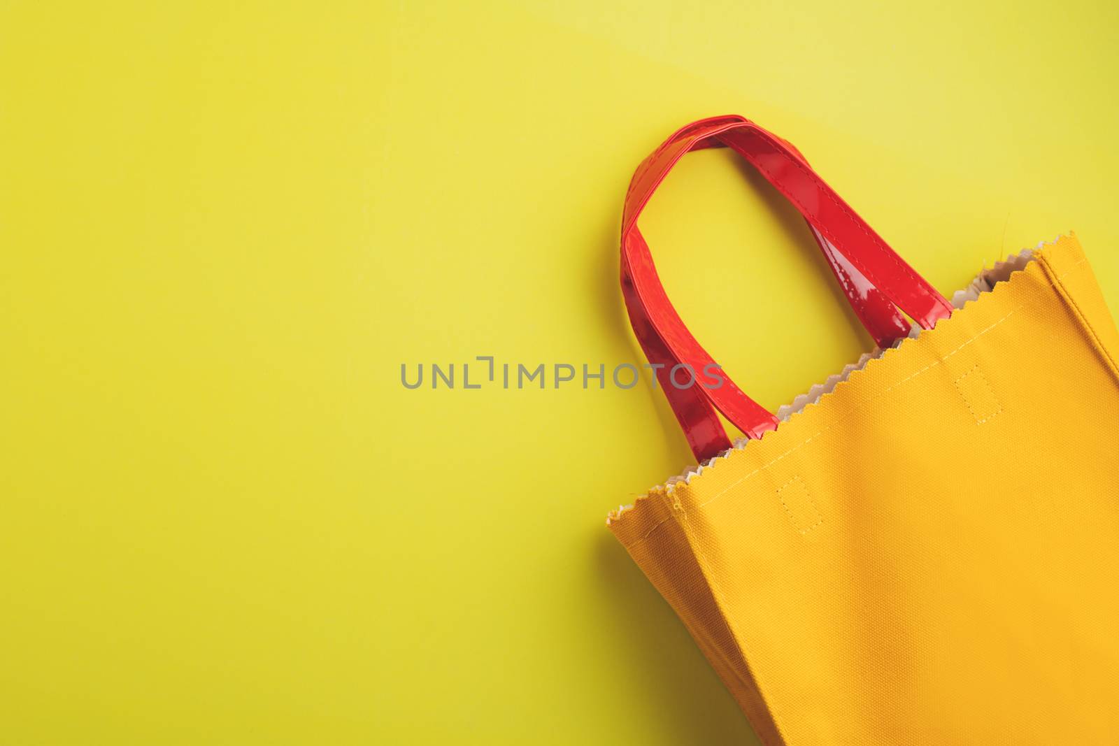 Yellow leather reusable bag on yellow background with copy space for green environmentally friendly concept 