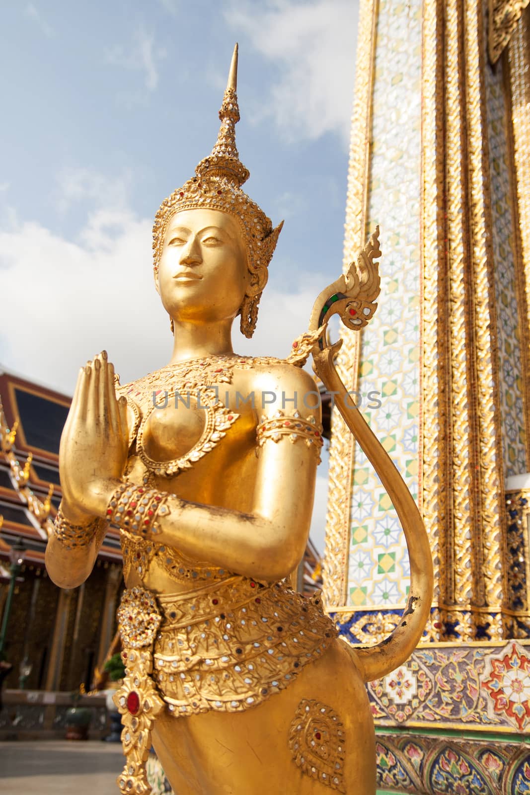 Golden Kinnari statue at Temple of Emerald Buddha (Wat Phra Kaew) in Grand Royal Palace. Kinnari is half-bird, half-woman creature at south-east Asian Buddhist mythology. Wat Phra Kaew is popular famous tourist attraction in Bangkok, landmark of Thailand, Southeast Asia by asiandelight