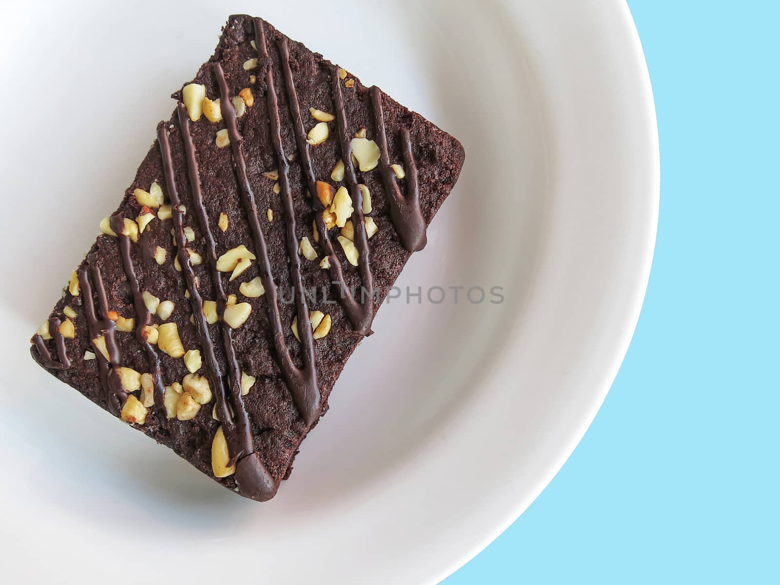 Chocolate brownies on a white plate, top view. blue background by asiandelight