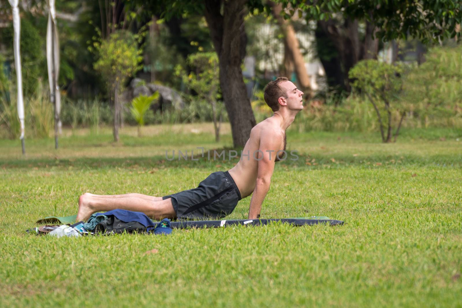 Man exercising by yoga in a outdoor park by PongMoji