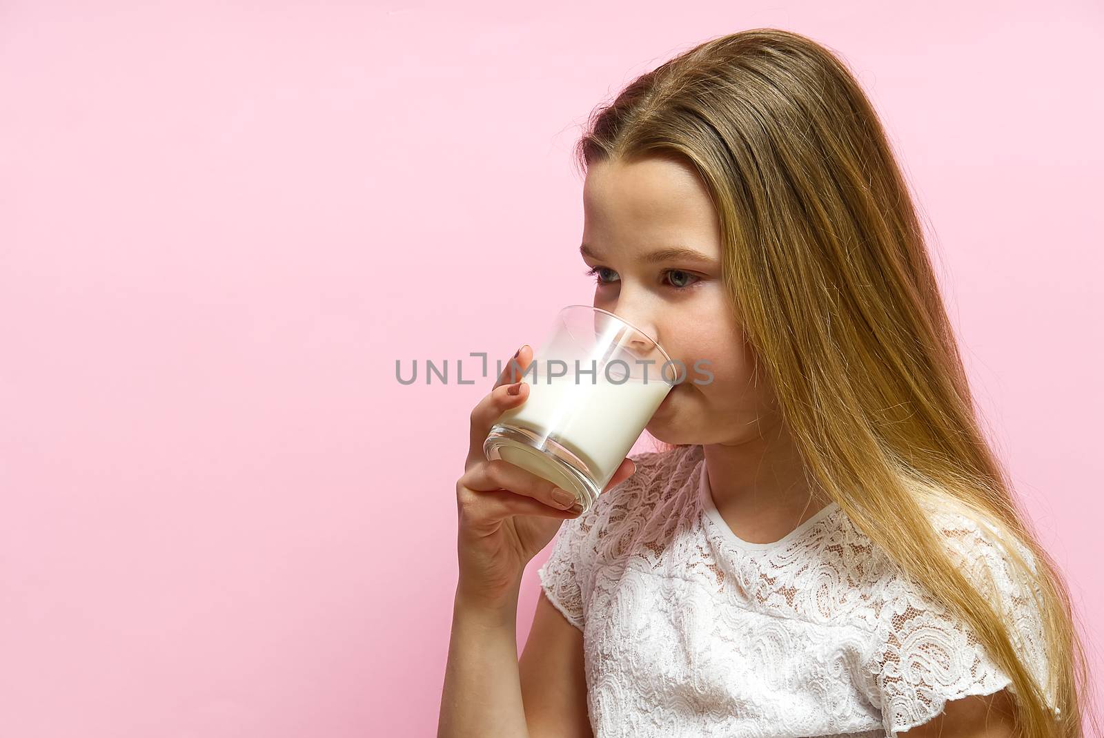 girl with pigtails and milk mustache drinks milk on pink background. by PhotoTime