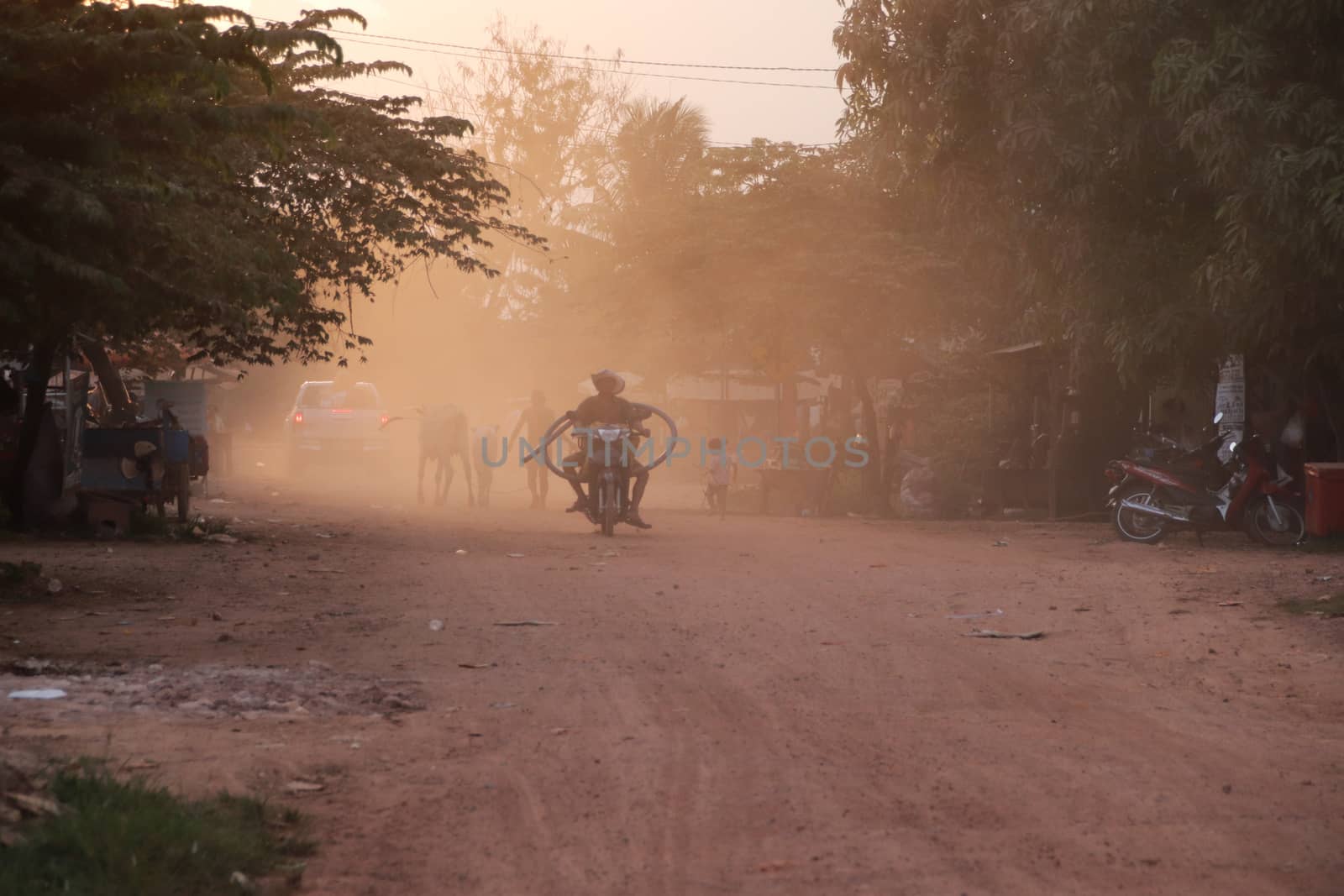 Motorbike driving on a dusty dirt road in the remote countryside of Cambodia