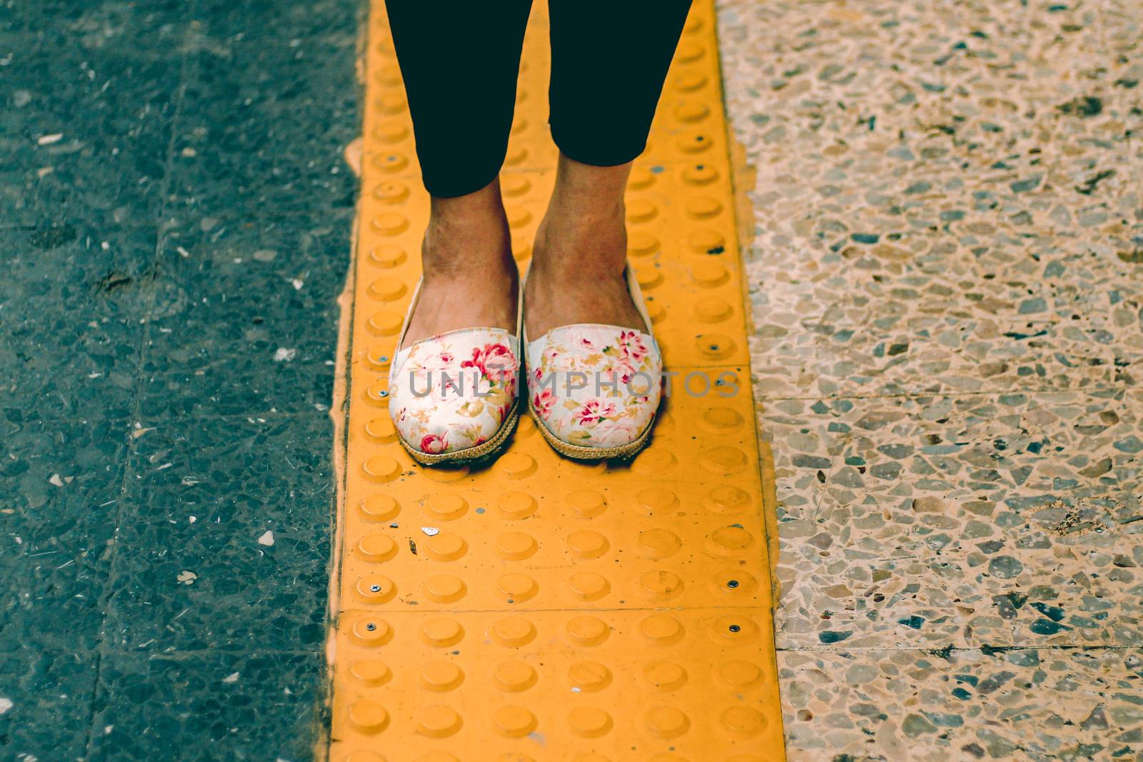 Woman wearing doll shoes standing on a yellow line showing concept of social distancing, isolation, the new normal lifestyle and travel during the covid-19 pandemic