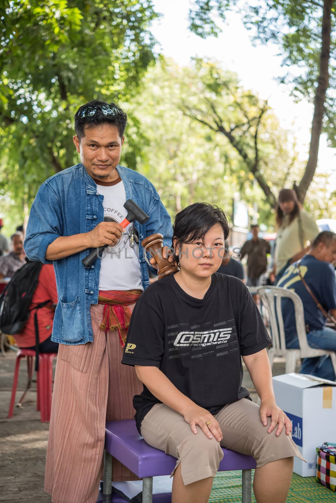 Bangkok, Thailand - July 28, 2017 : Unidentified Thai woman to take of service Thai massage by wooden hammer for treat aches and pains. The service comes in the outdoor garden.