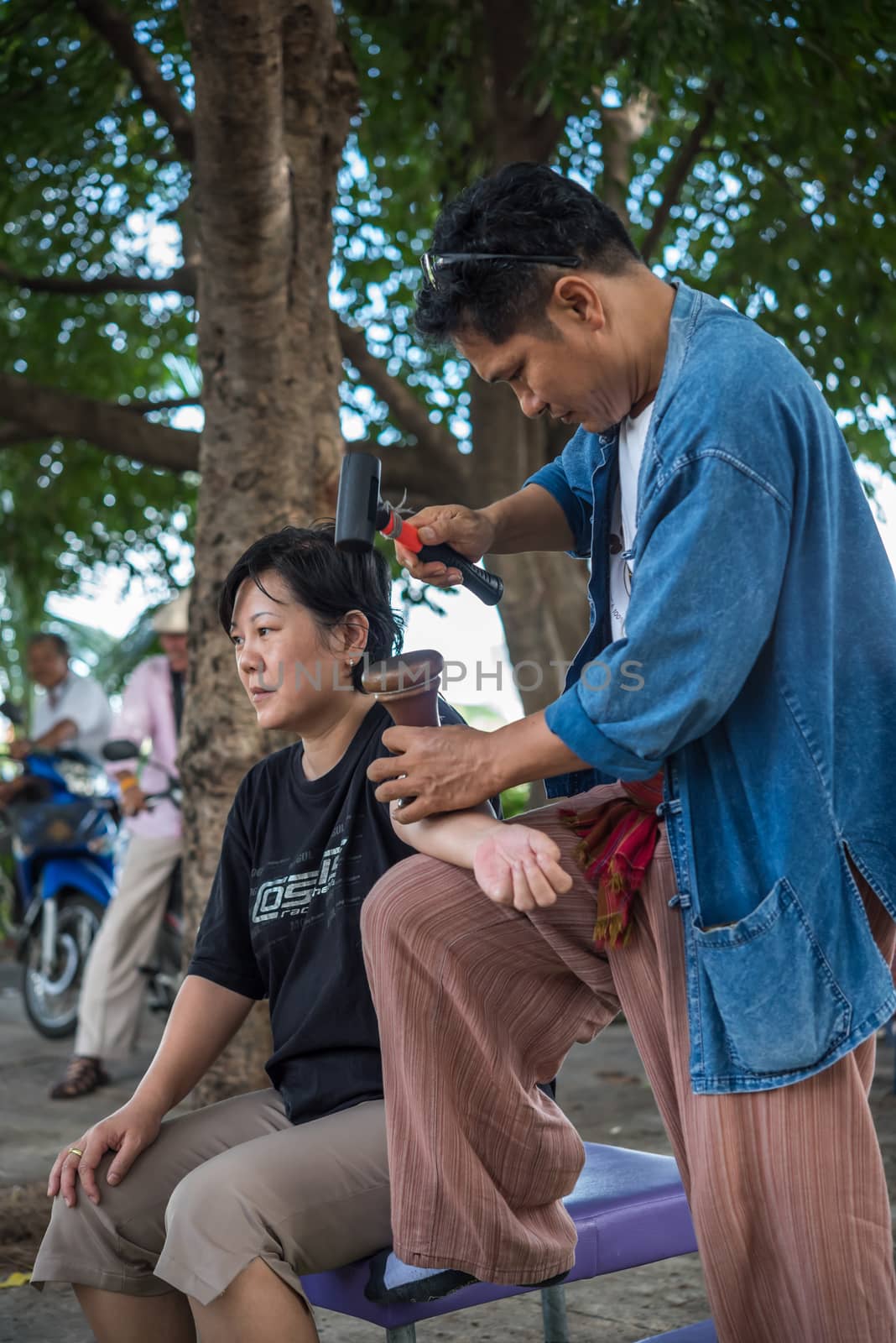 Bangkok, Thailand - July 28, 2017 : Unidentified Thai woman to take of service Thai massage by wooden hammer for treat aches and pains. The service comes in the outdoor garden.