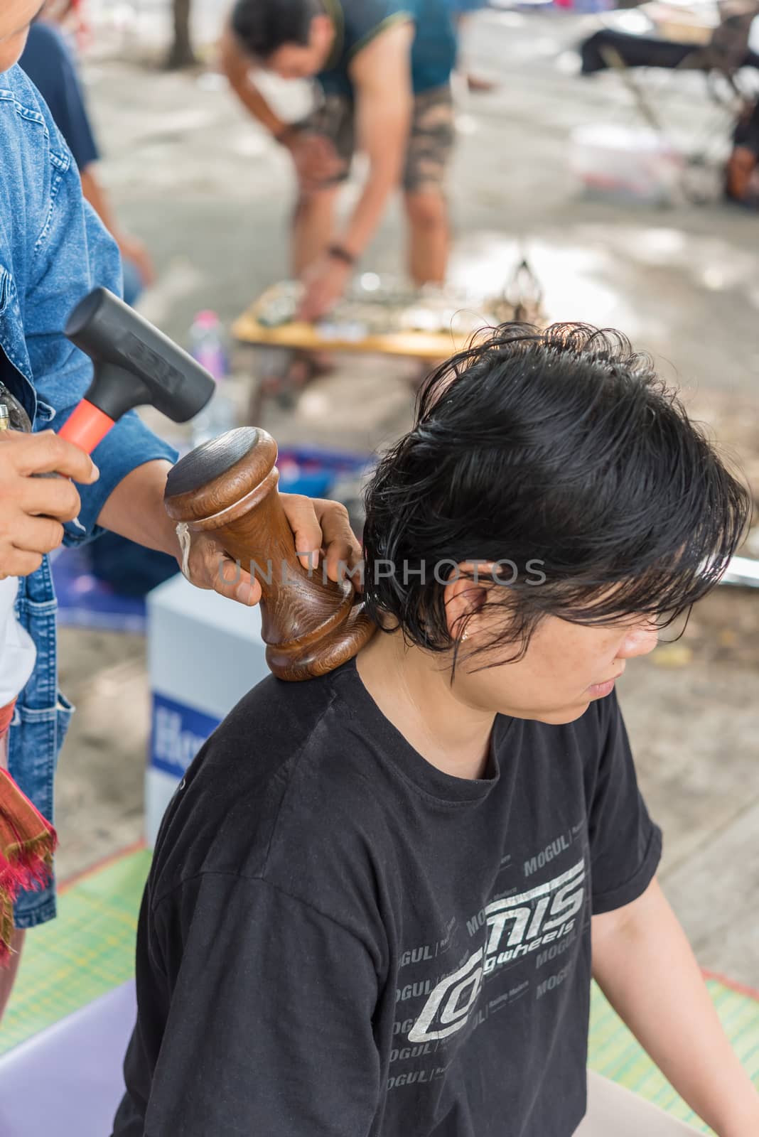 Bangkok, Thailand - July 28, 2017 : Unidentified Thai woman to take of service Thai massage by wooden hammer for treat aches and pains. The service comes in the outdoor garden.