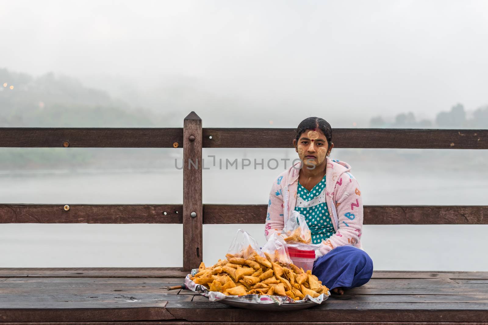 Kanchanaburi, Thailand - March 2, 2018 : Mon woman sale food or dessert on Mon Bridge, Wooden Bridge in Tambon Nong Lu, Amphoe Sangkhla Buri, Chang Wat Kanchanaburi