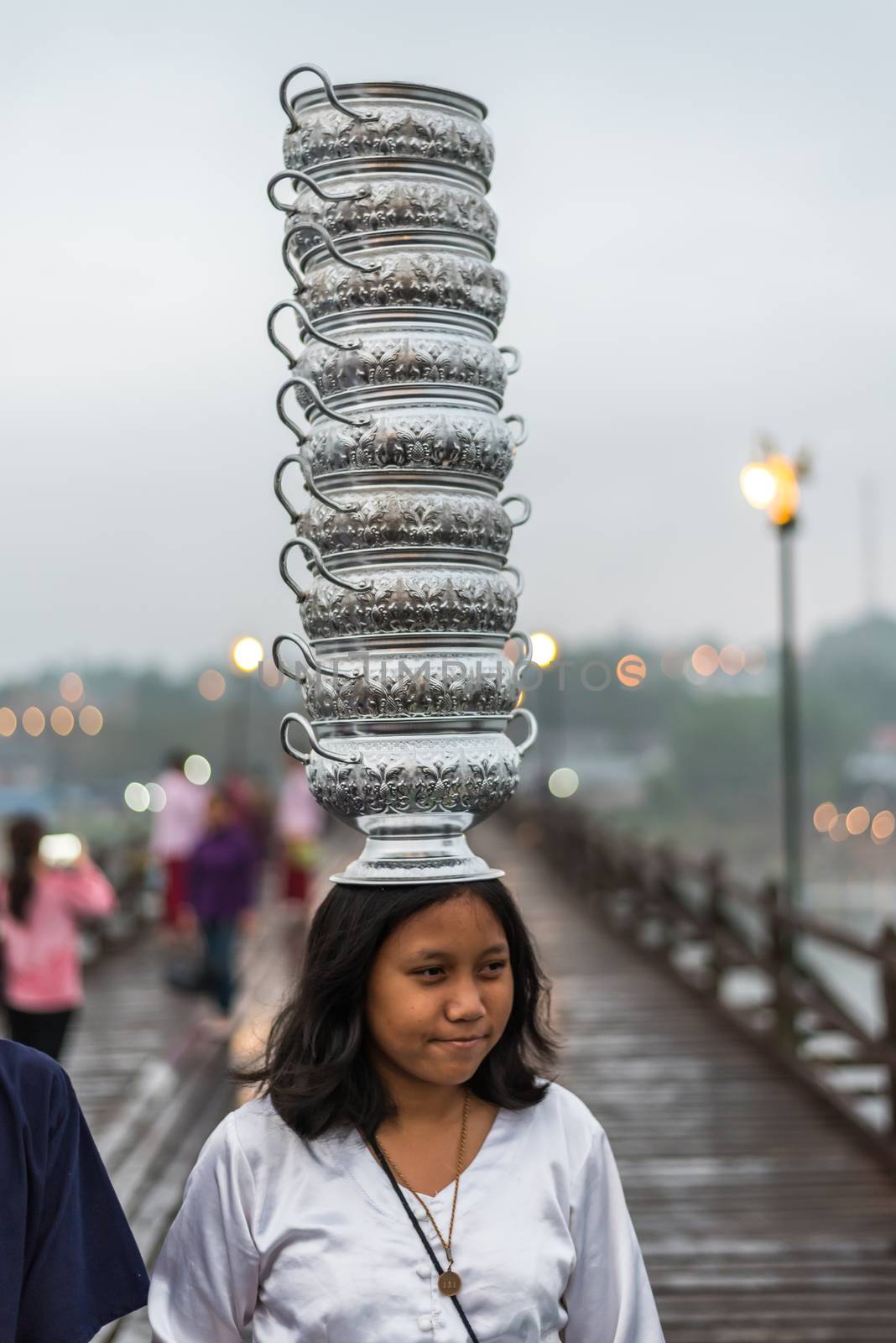 Kanchanaburi, Thailand - March 2, 2018 : Mon woman carry bowl on the head for transport walking on Mon Bridge, Wooden Bridge in Tambon Nong Lu, Amphoe Sangkhla Buri, Chang Wat Kanchanaburi