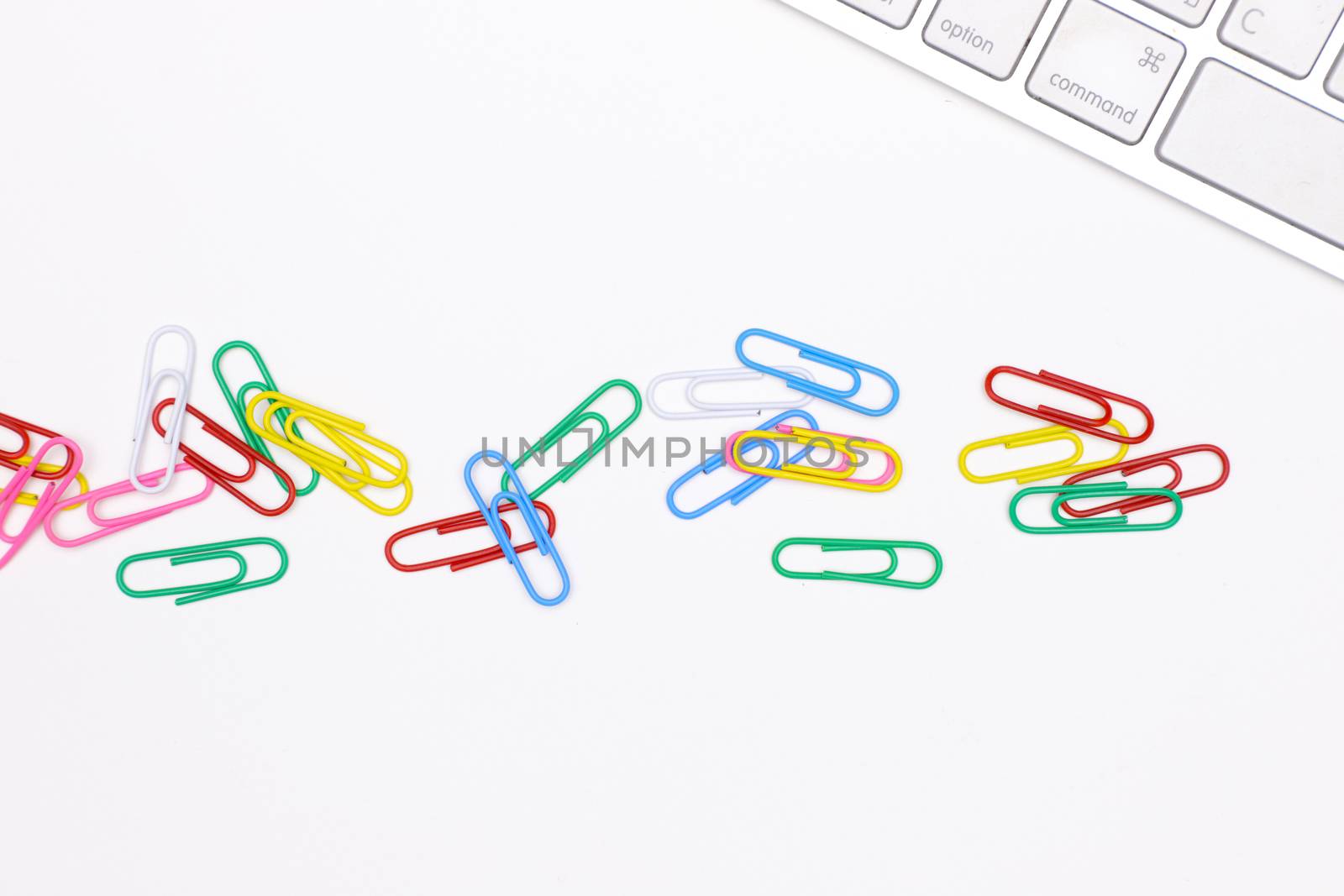 colorful paper clips on an office desk with a white keyboard