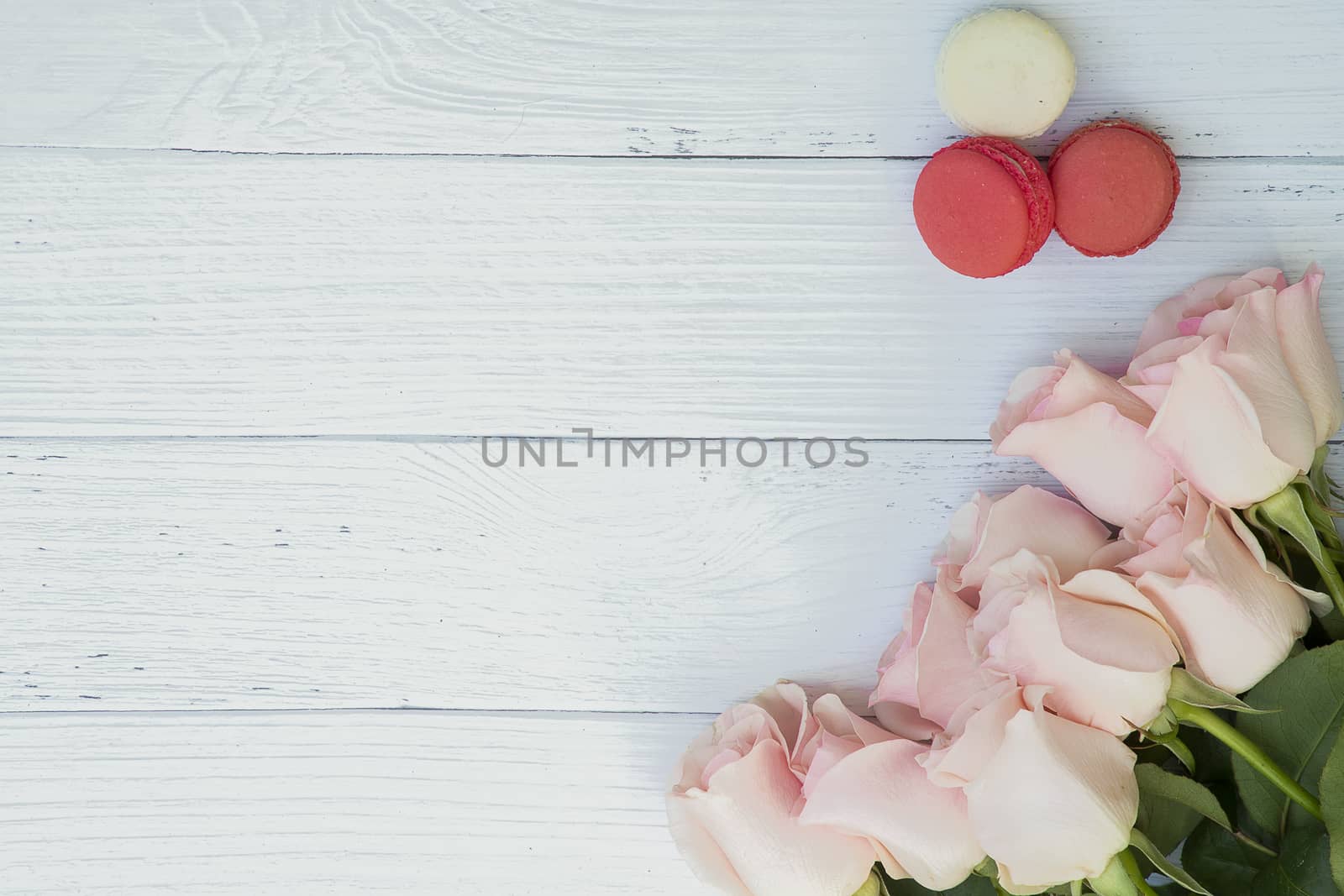 Beautiful bouquet of soft pink roses and pieces of macaroon on wood background. Love, Romance, Valentine's, Anniversary.