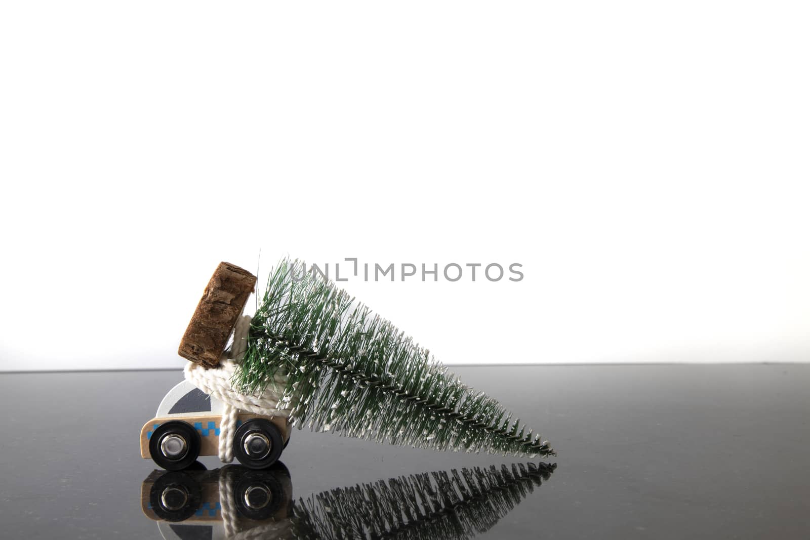 Image of a toy ambulance and a miniature christmas tree. Isolated black and white background with reflections of the subjects on the smooth surface.