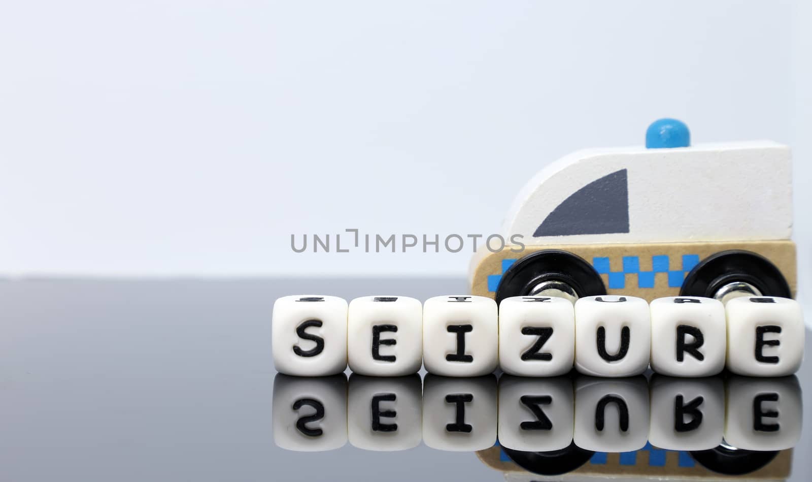 image of letters spelling a word seizure and a model ambulance on a reflecting background