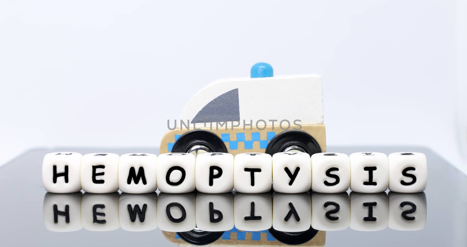 image of letters spelling a word hemoptysis and a model ambulance on a reflecting background