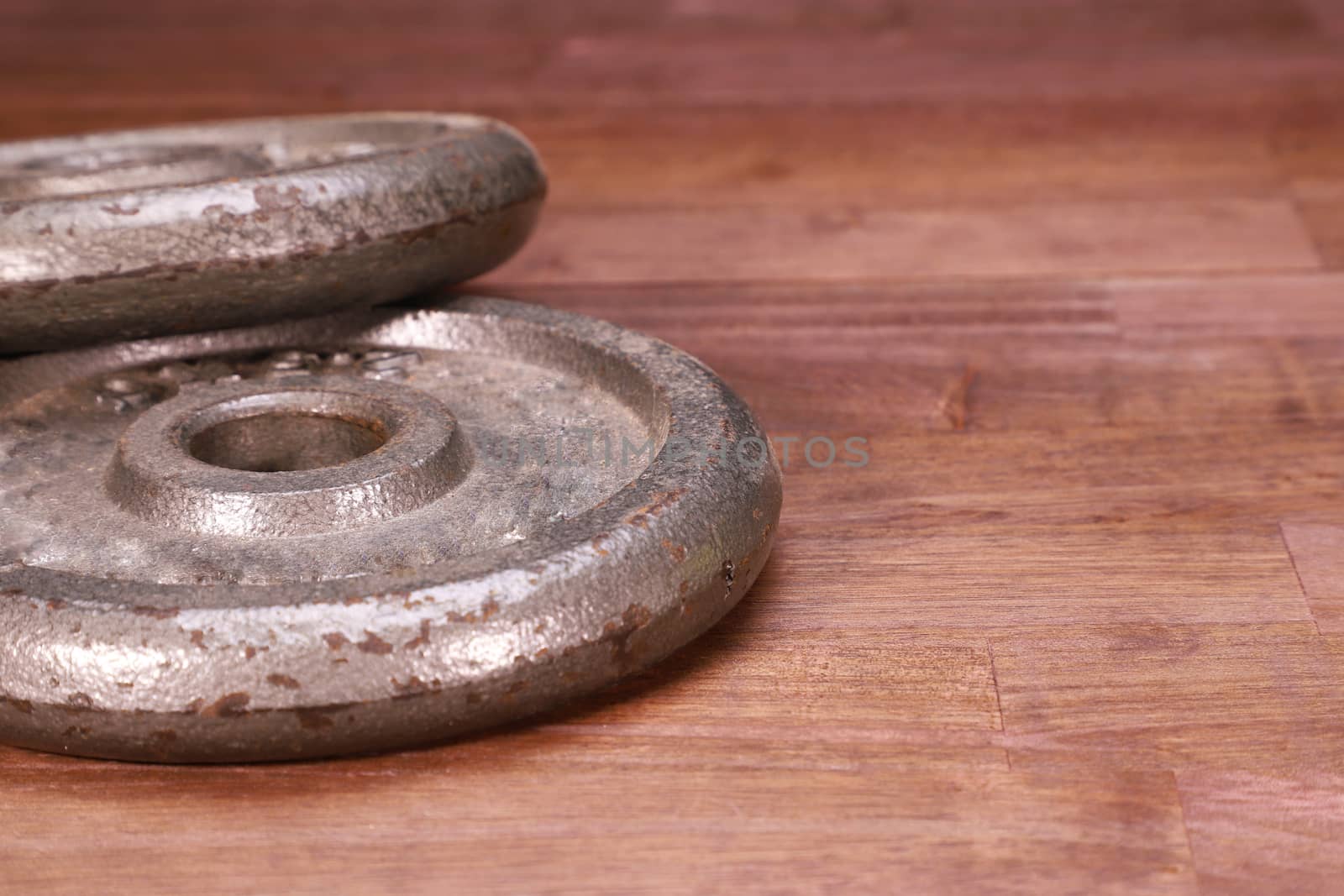 two old weight plates on brown natural wood background