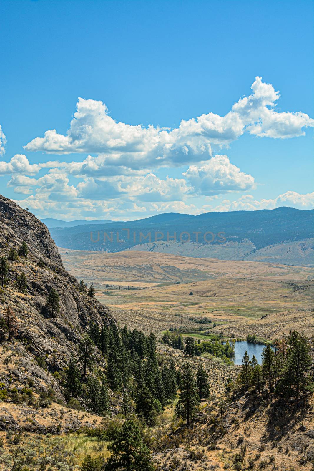 Beautiful overview of Okanagan valley with small lake downhill on bright sunny day