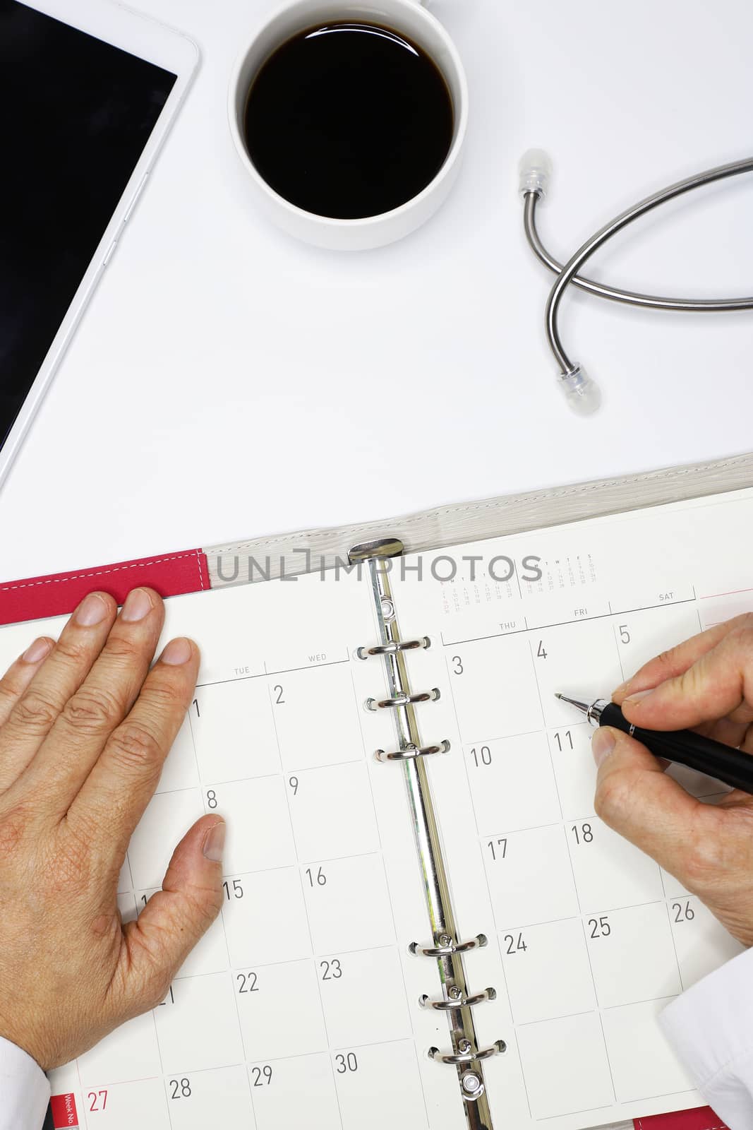 a doctor using a telecommunicating device (conceptualizing) to set up an appointment with the patient, high angle view, on clean desk background