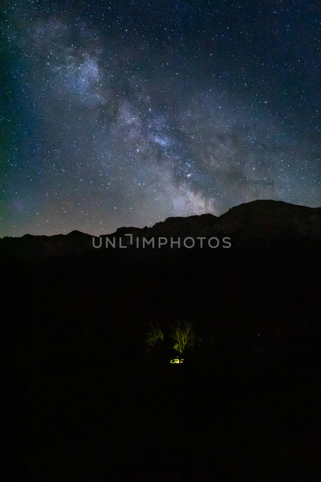 Night light photography of a house located under the Milky Way in a starry sky with the Pyrenees mountains of Cadi Moixero