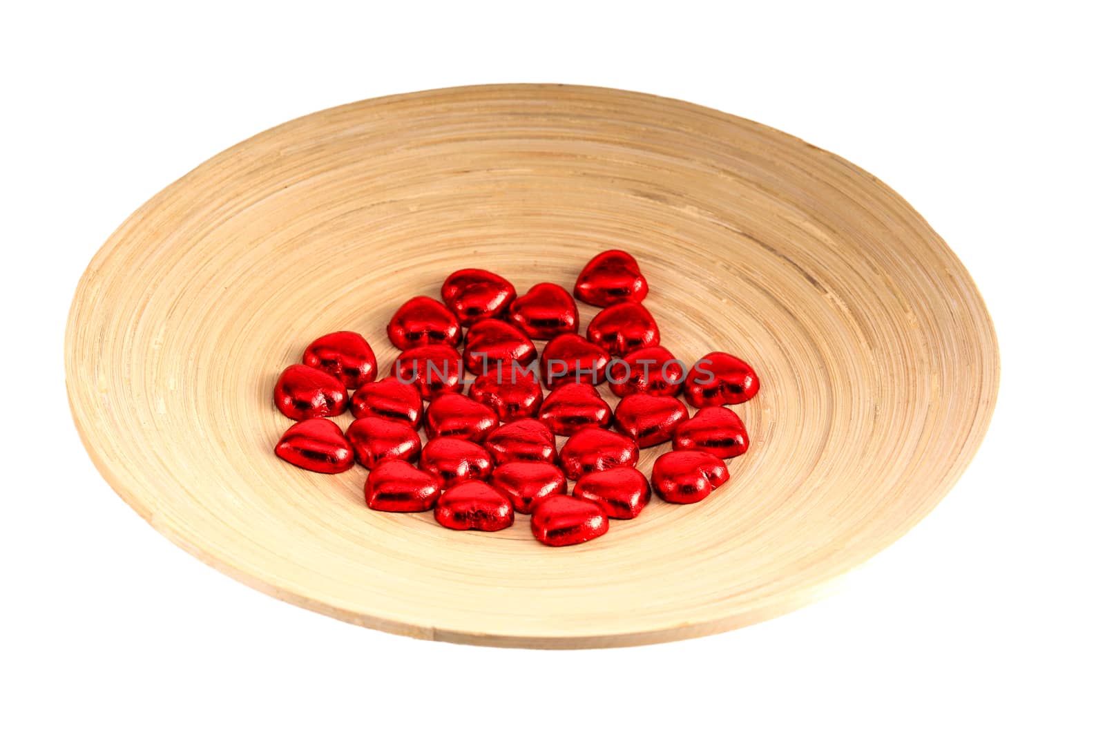 red heart-shaped chocolate candies on a bamboo plate, isolated on white background, Valentines' day concept