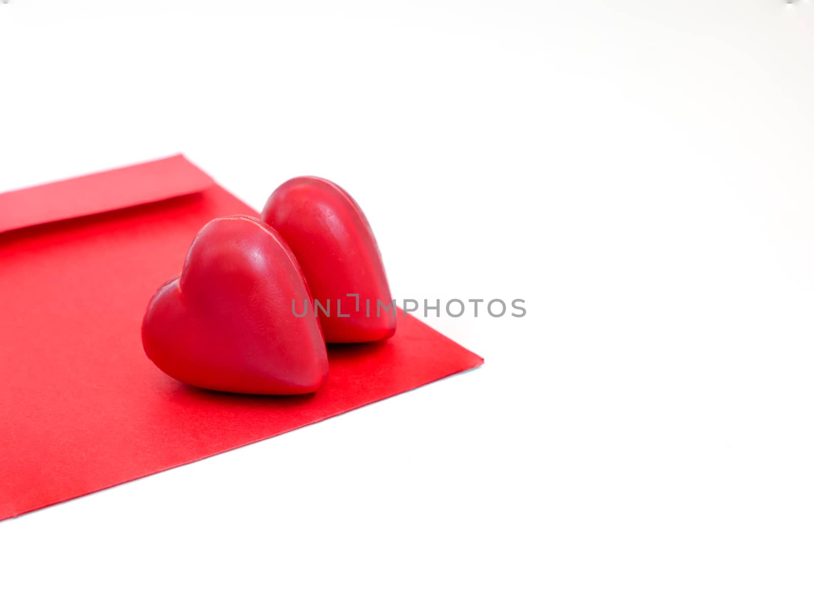 a red love letter envelope with two heart-shaped chocolate candies, isolated on white background, love, romance, Valentines' Day concept