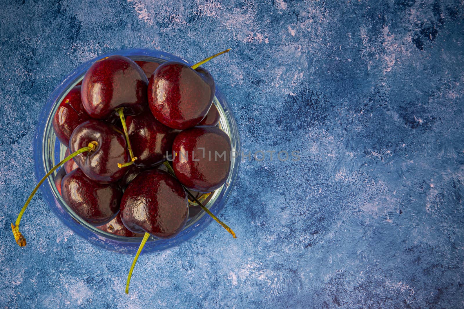 Fresh cherries in a glass of water by Nawoot