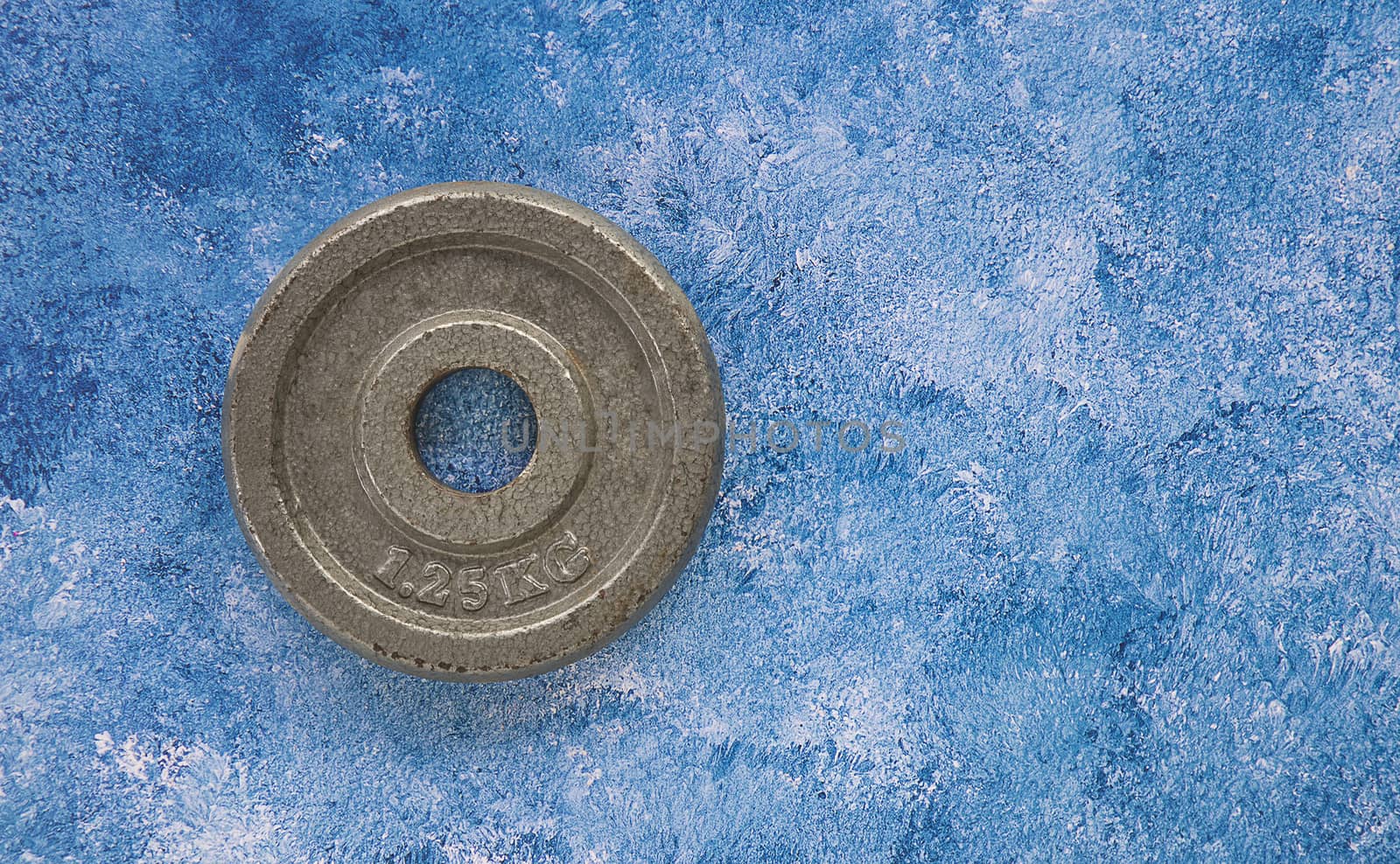 An old rusty metal weight plate on a blue and wihte acrycli paint background