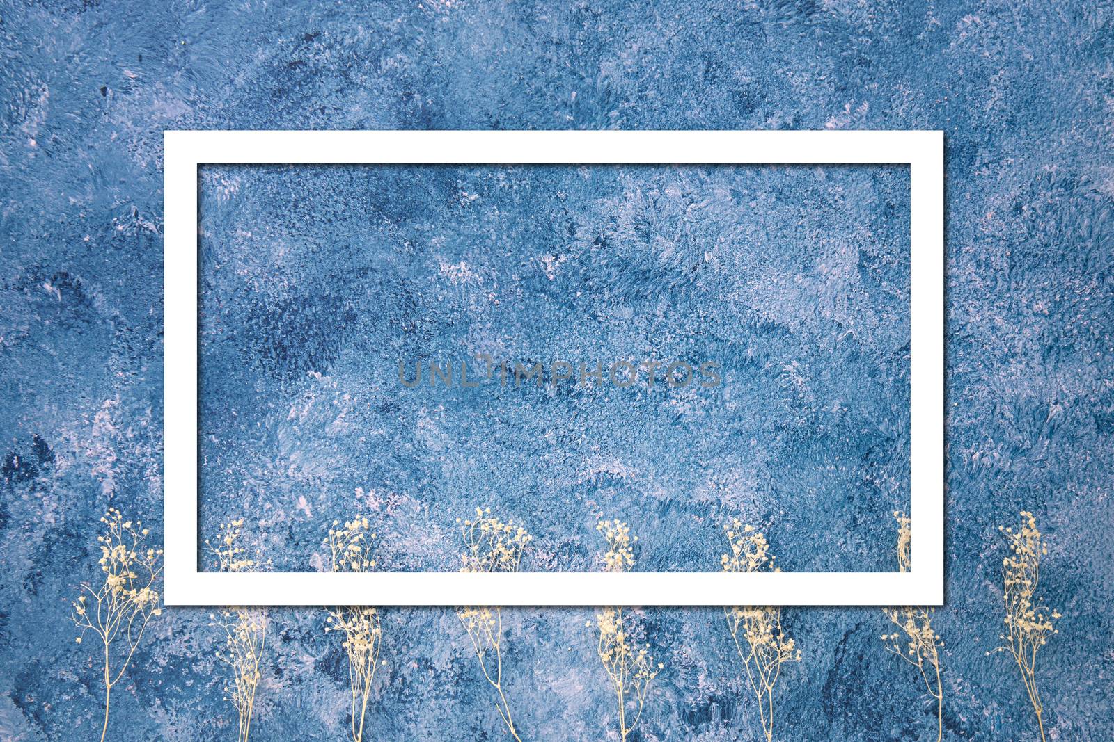Blue and white acrylic paint abstract background with dried flowers and white frame.