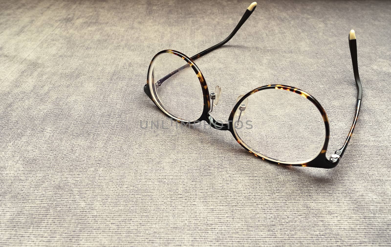 A pair of dark brown spectacles on a brown cotton sofa. Copy space.