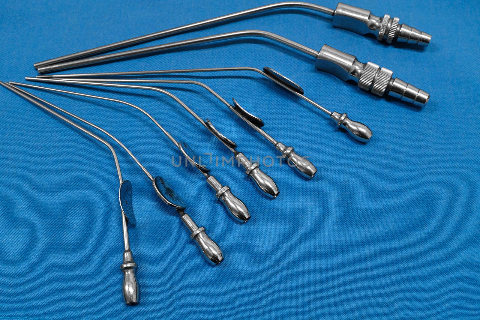 various sizes of ear suction cannula arranged in pattern on top of a blue cloth