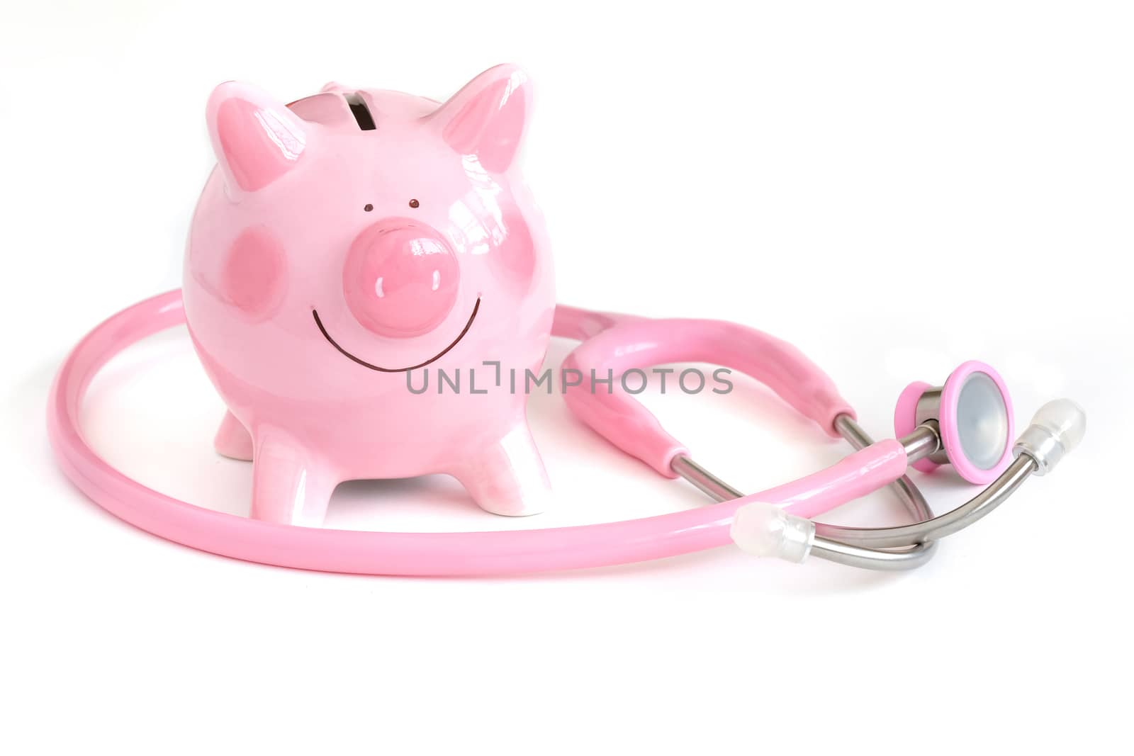 a cute pink ceramic piggy bank and a pink pediatric stehoscope. Isolated on white background. Insurance, Saving Health Care Cost.