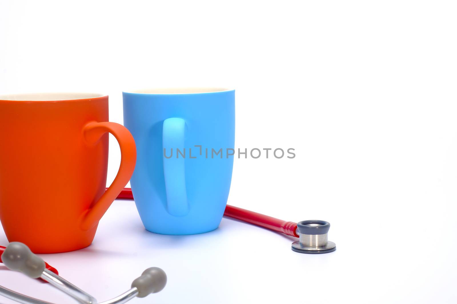 a red stethoscope and two colorful coffee mugs