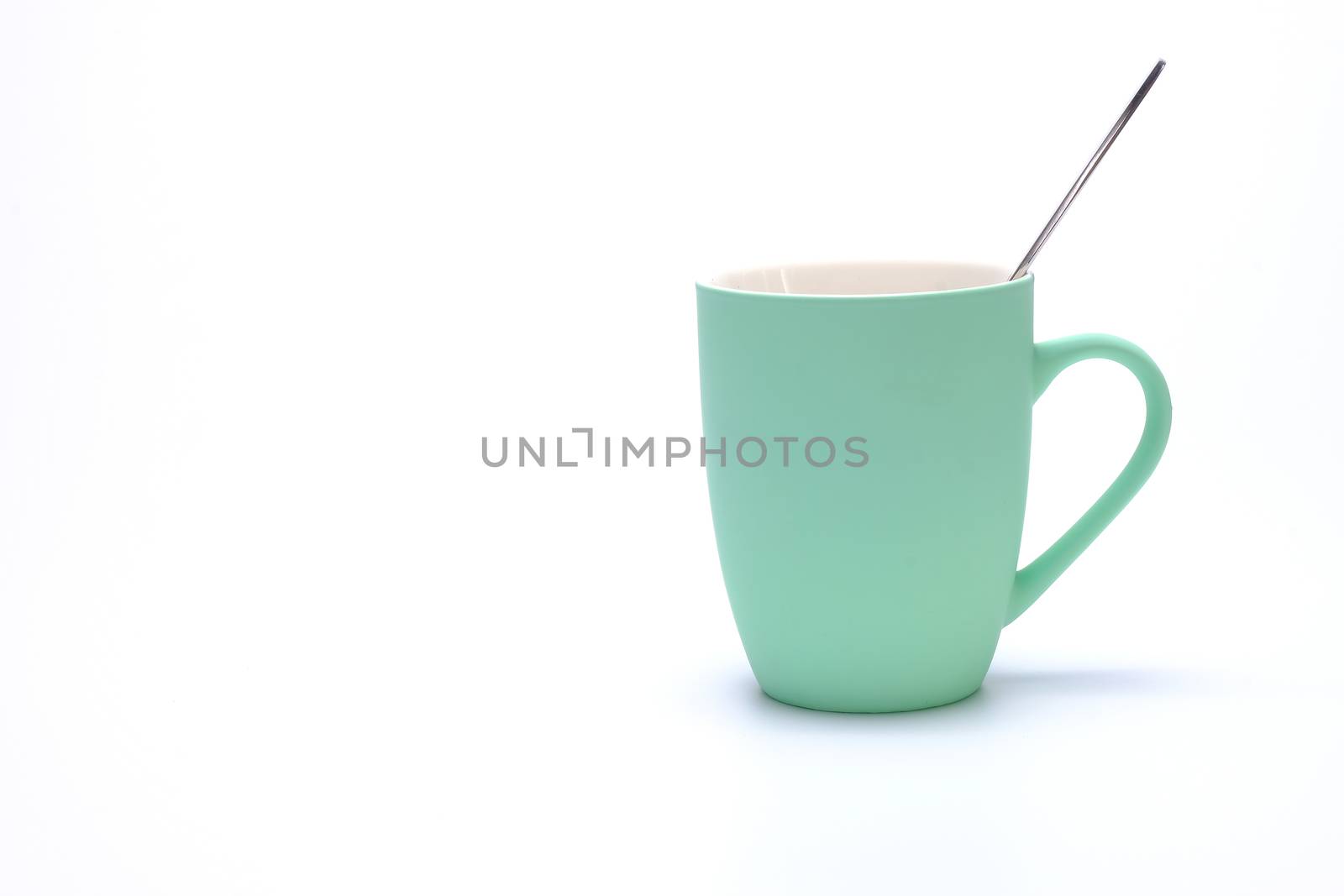 green coffee mug with spoon isolated on white background