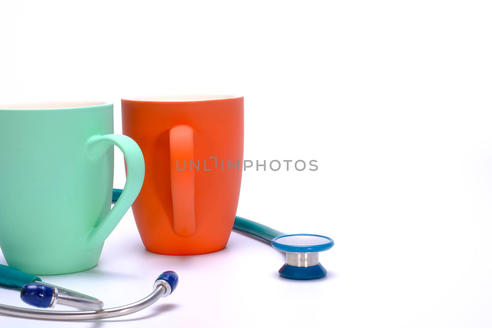a green stethoscope and two green and orange coffee mugs on white background