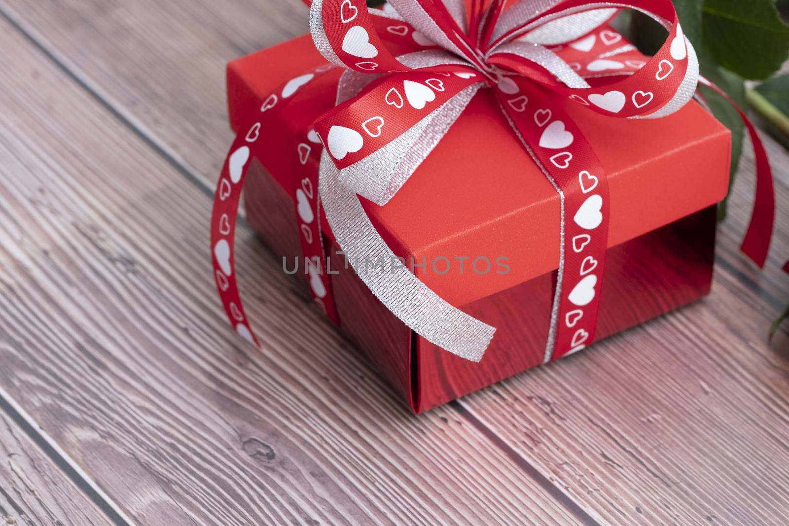 A beautiful red gift box with delicate red and white ribbons, isolated on white background. A present for Holidays, Christmas, New Year, Valentine's, Birthday, Anniversary.