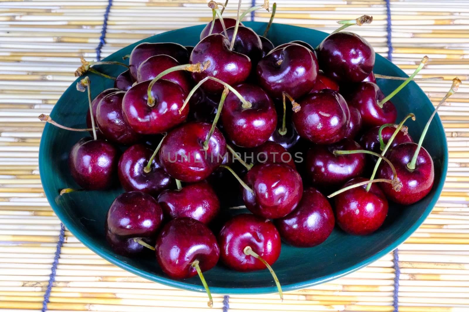 A bunch of cherries on a green ceramic palte