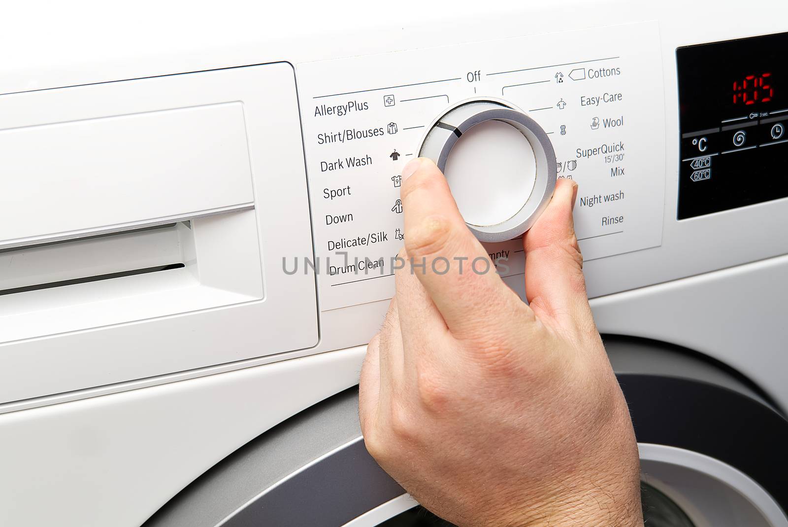 The man sets the program and turns on the washing machine. Close-up Of Person Hand Pressing Button Of Washing Machine For Clothes Laundry.