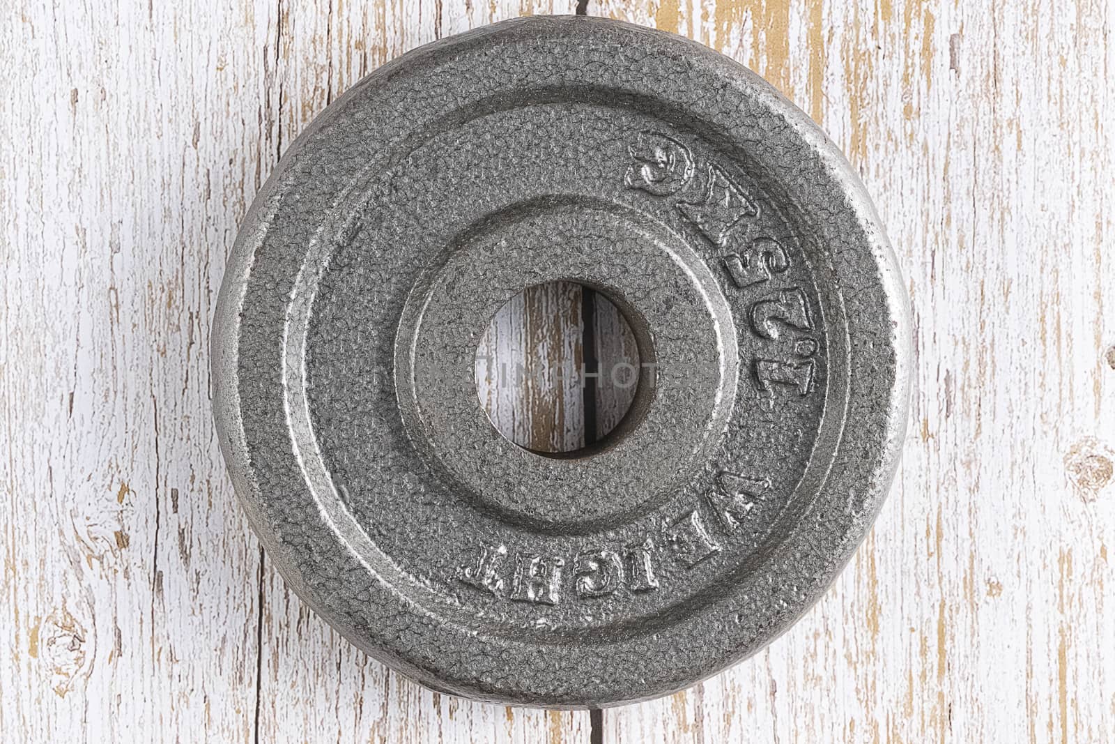 A metal weight plate on brown wooden background