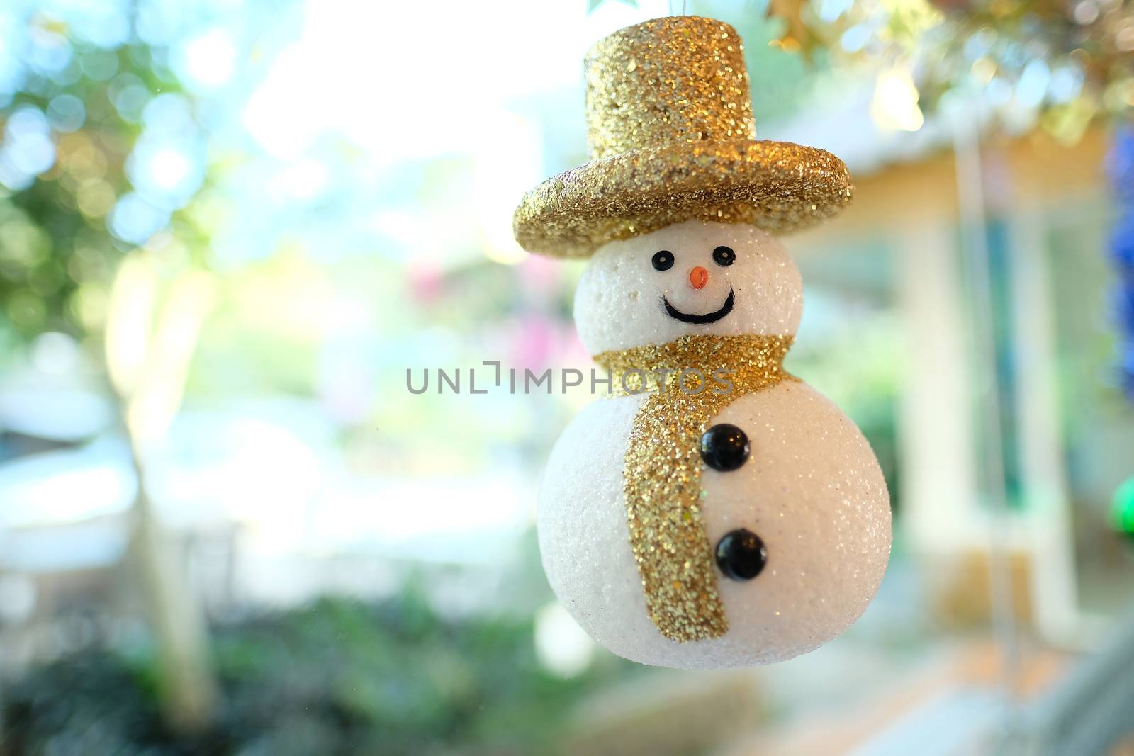 a cute decorative snowman with a cute golden hat smailing joyfully by the glass window in the restaurant