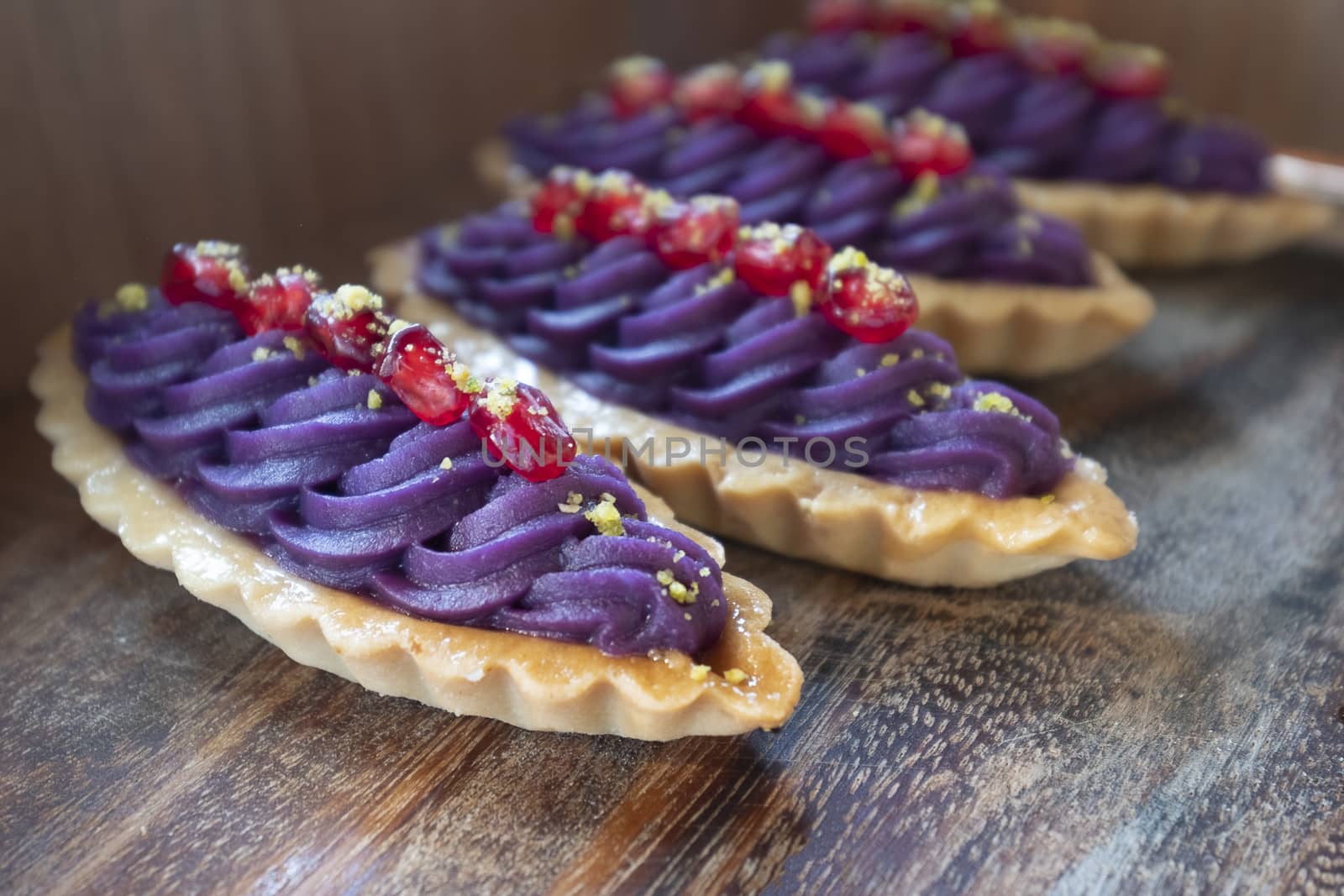 Purple yam and pomegranate tart on a wood table. Selective focus.