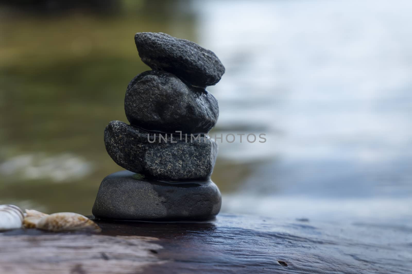 Small stack of pebbles or stones in a stream carefully balanced on each other with rippling sunlit water flowing past